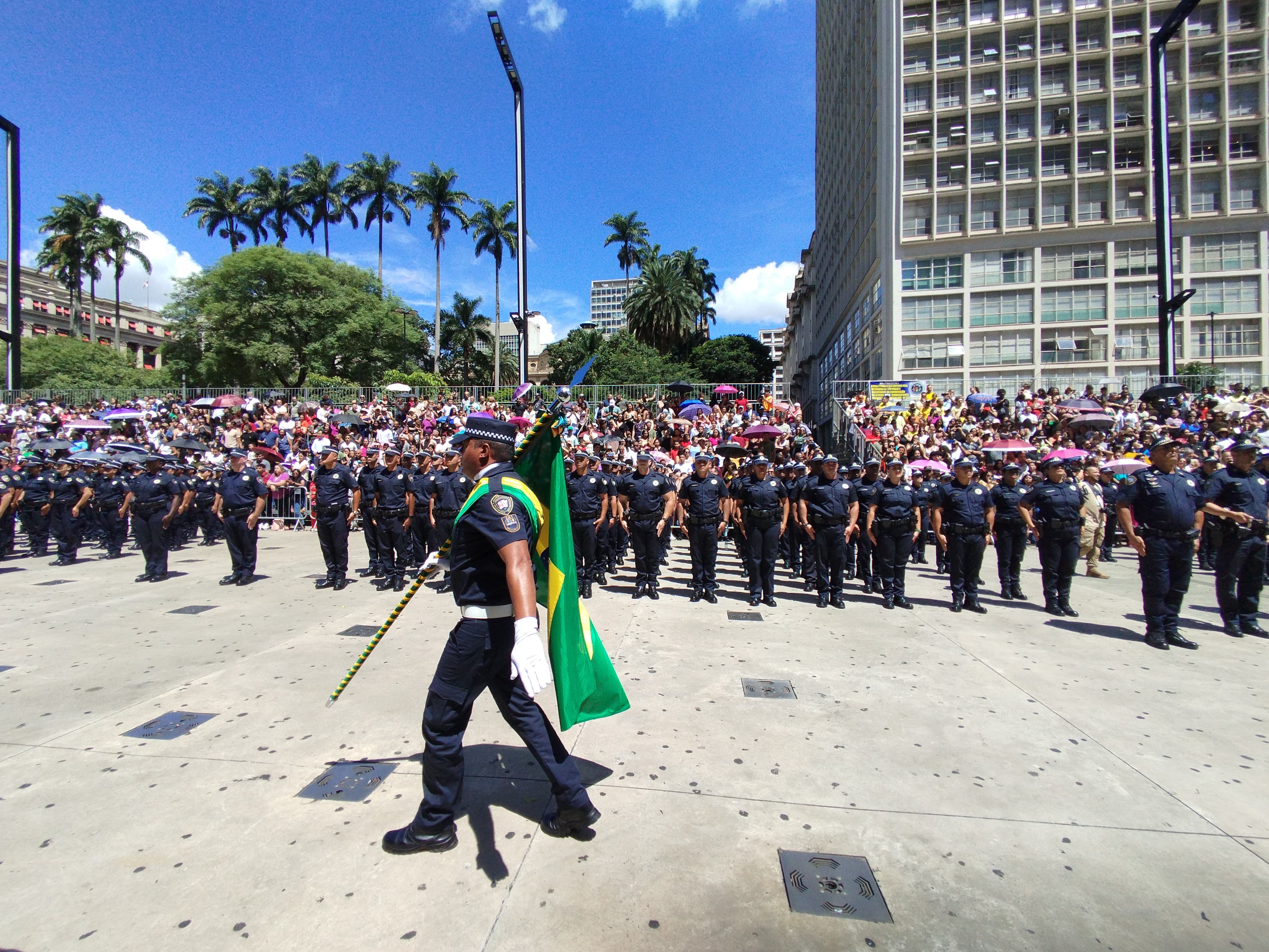 Inspetor da GCM com bandeira do Brasil em frente ao novo efetivo honrando a bandeira em cerimônia no Vale do Anhangabaú, São Paulo