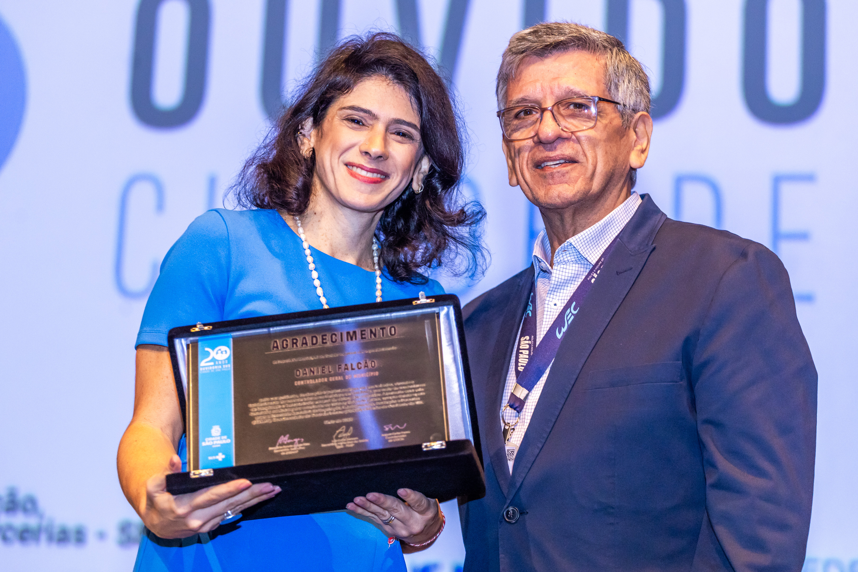 Foto: Chefe de Gabinete, Thalita Abdala, segurando uma placa de homenagem.