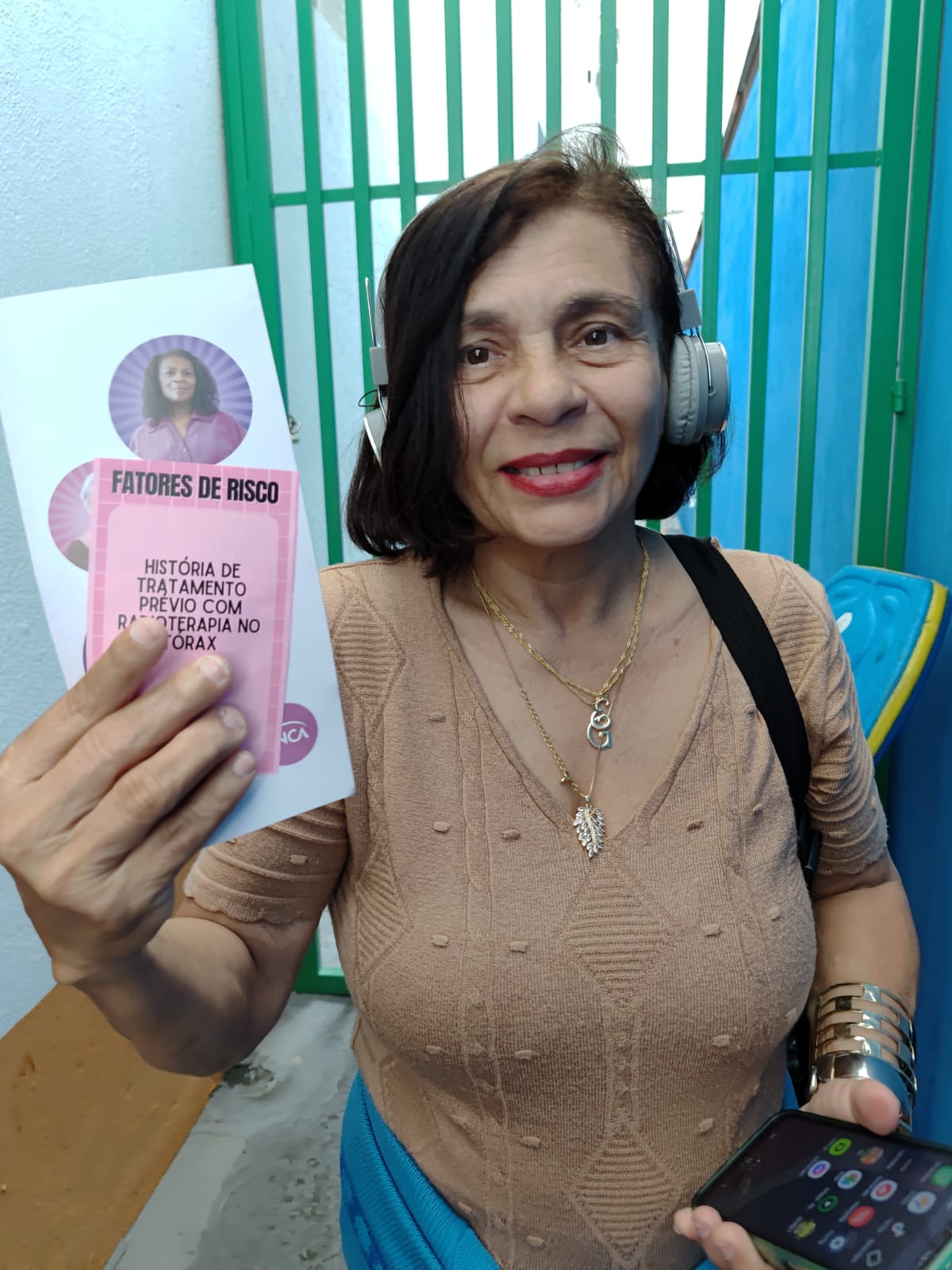 A acolhida Eunice mostra para a câmera folhetos informativos sobre a prevenção ao câncer de mama