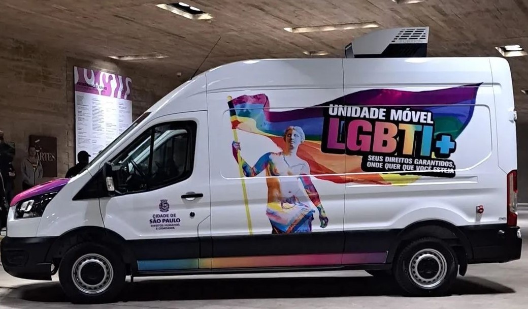 #PraTodosVerem: Foto da Unidade Móvel LGBTI+, uma van de cor predominante branca com logotipo e desenho de uma deusa portando uma bandeira com as cores do arco-iris