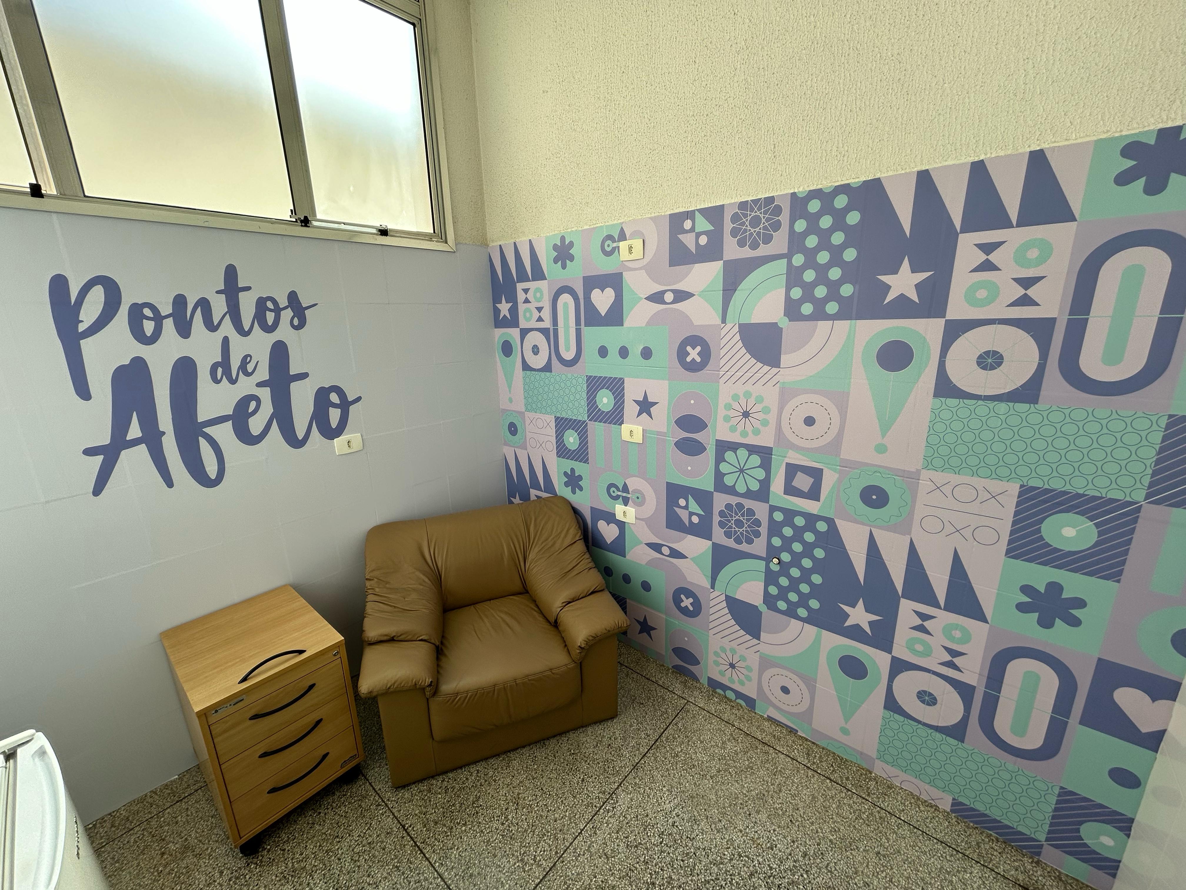 Sala com uma poltrona, um gaveteiro, nas paredes grafitado e palavra Pontos de Afeto