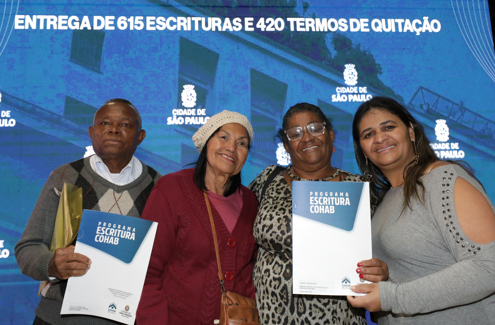 Quatro pessoas segurando suas escrituras entregues no evento