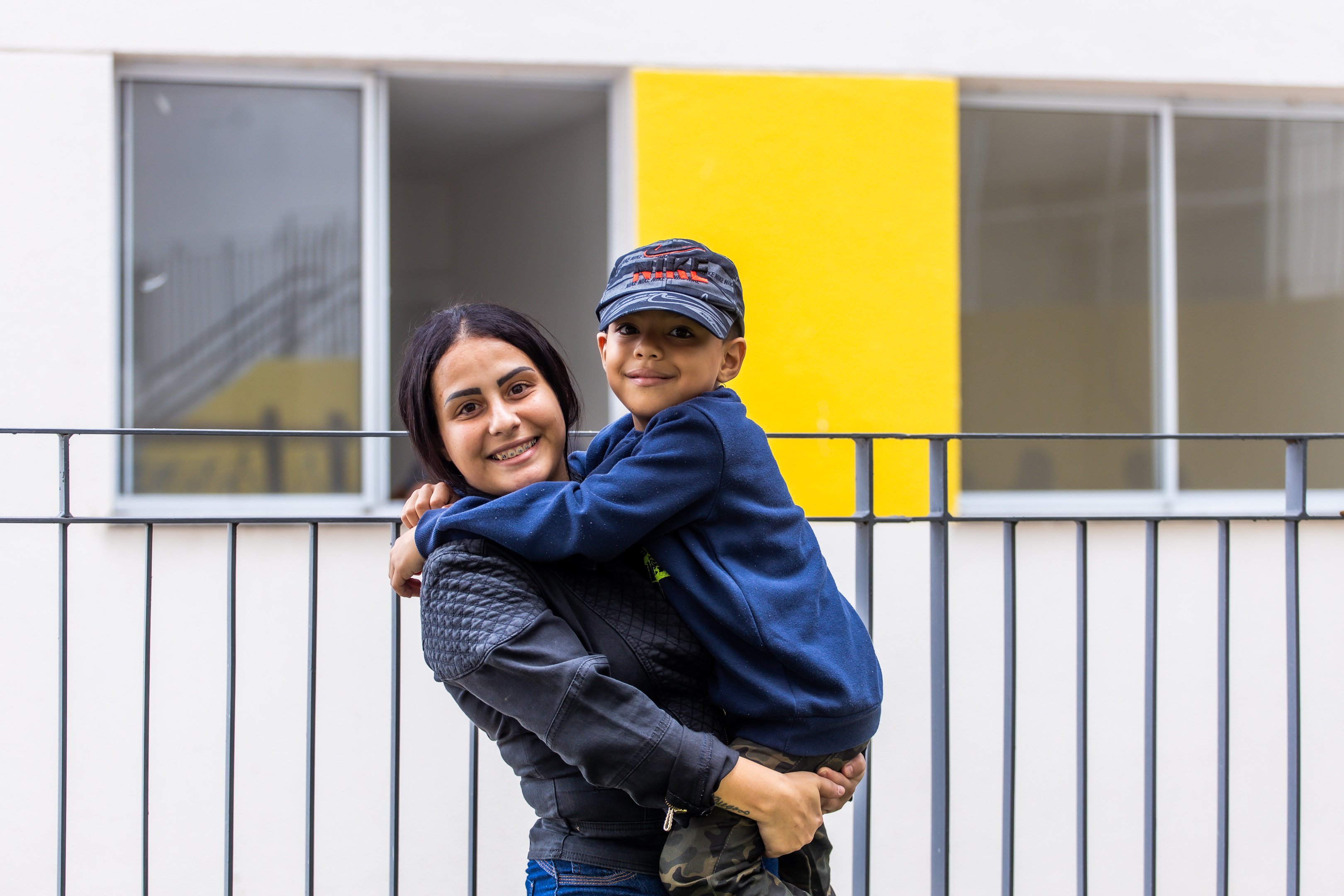 Uma mulher, com seu filho no colo, sorriem