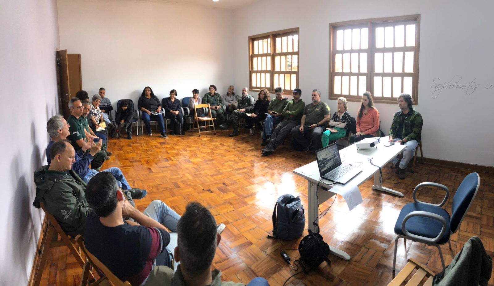 Círculo de pessoas, reunidas e sentadas em cadeiras de madeira em uma sala para o terceiro Encontro de Gestão de Unidades de Conservação da Zona Sul. 